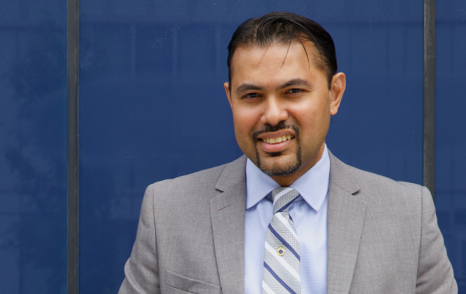 Man in suit standing against a blue wall