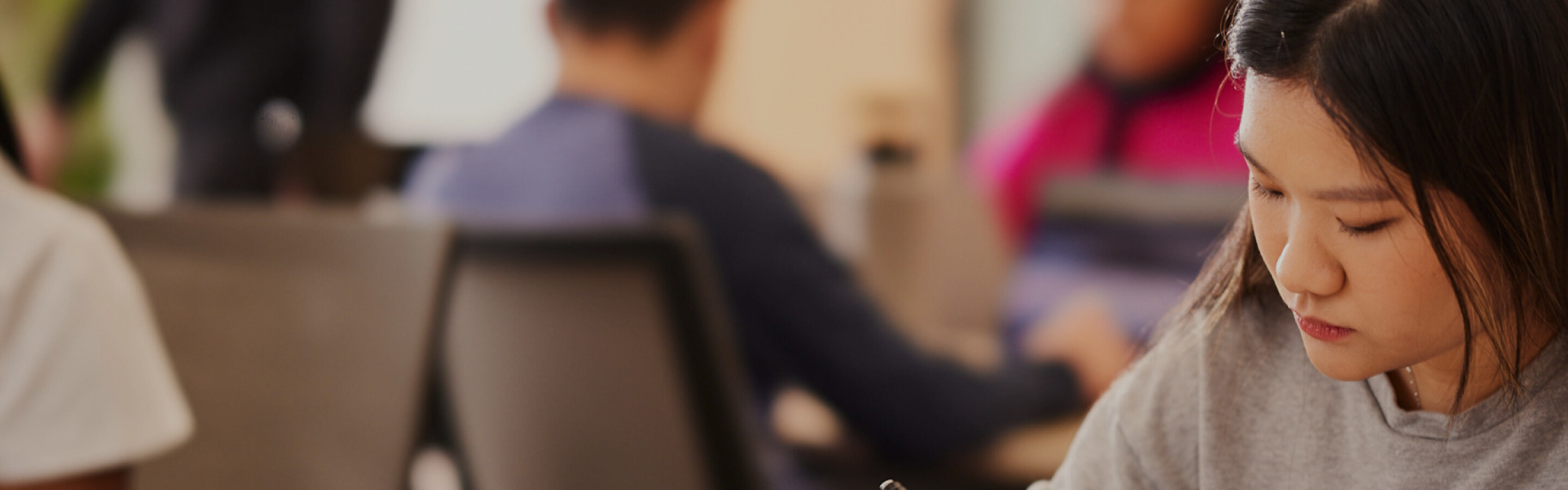 International student working at a desk in a room with other students